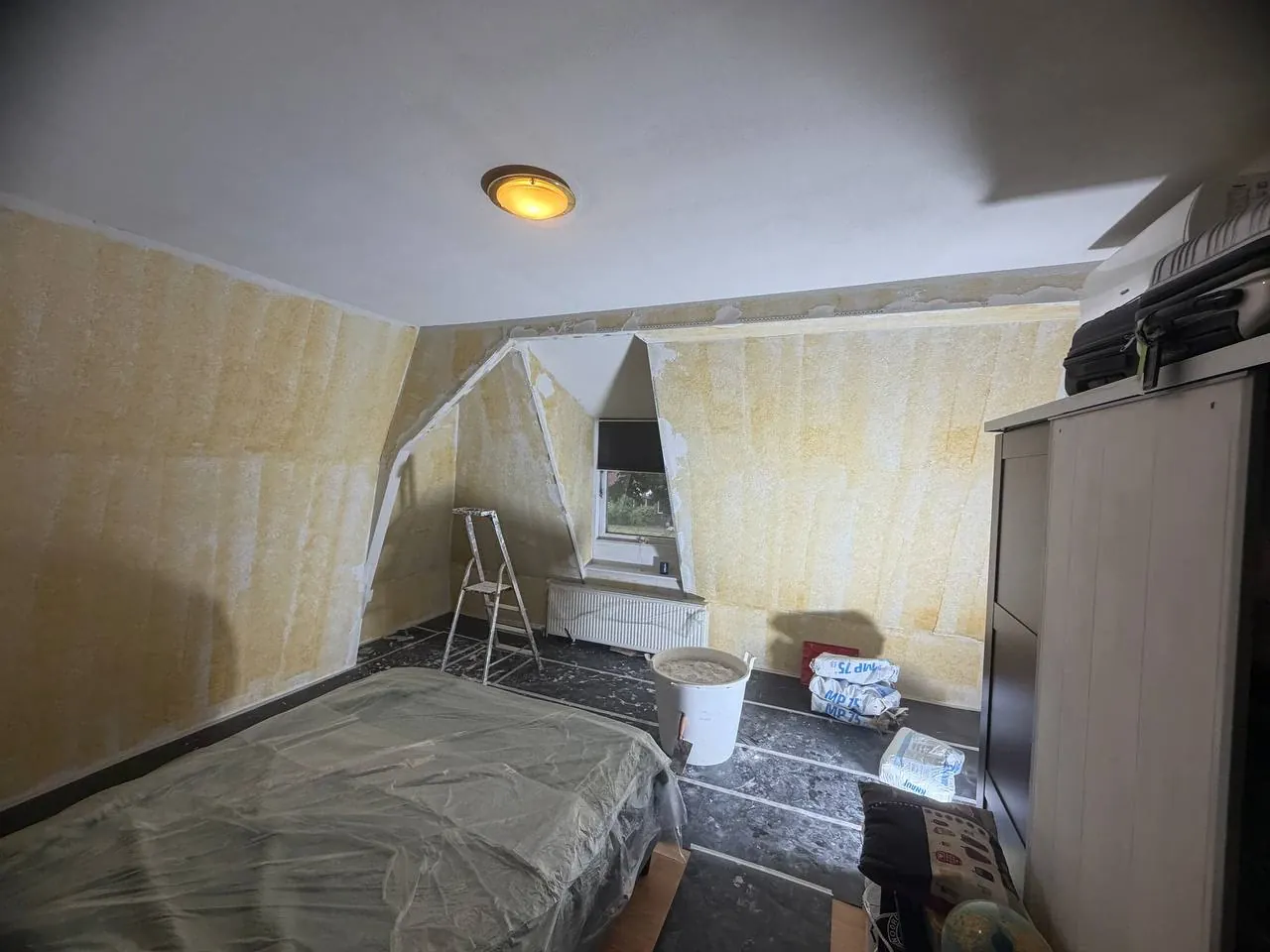 Slaapkamer onder schuin dak vóór het stucen, met gele structuurwanden